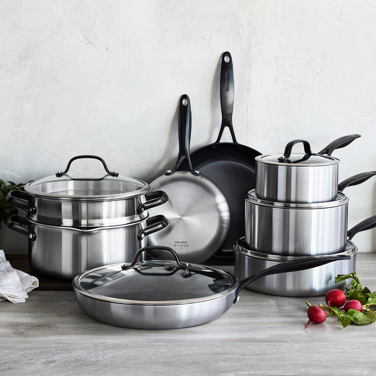 GreenPan ceramic cookware set with pots, pans, and lids on a kitchen counter, fresh radishes beside them.