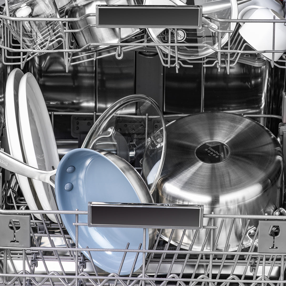 Open dishwasher with clean ceramic nonstick frypans inside, handles visible, arranged on the rack.