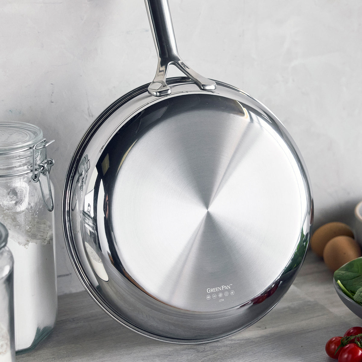Hybrid ceramic nonstick pan with a black handle standing upright on a kitchen counter.