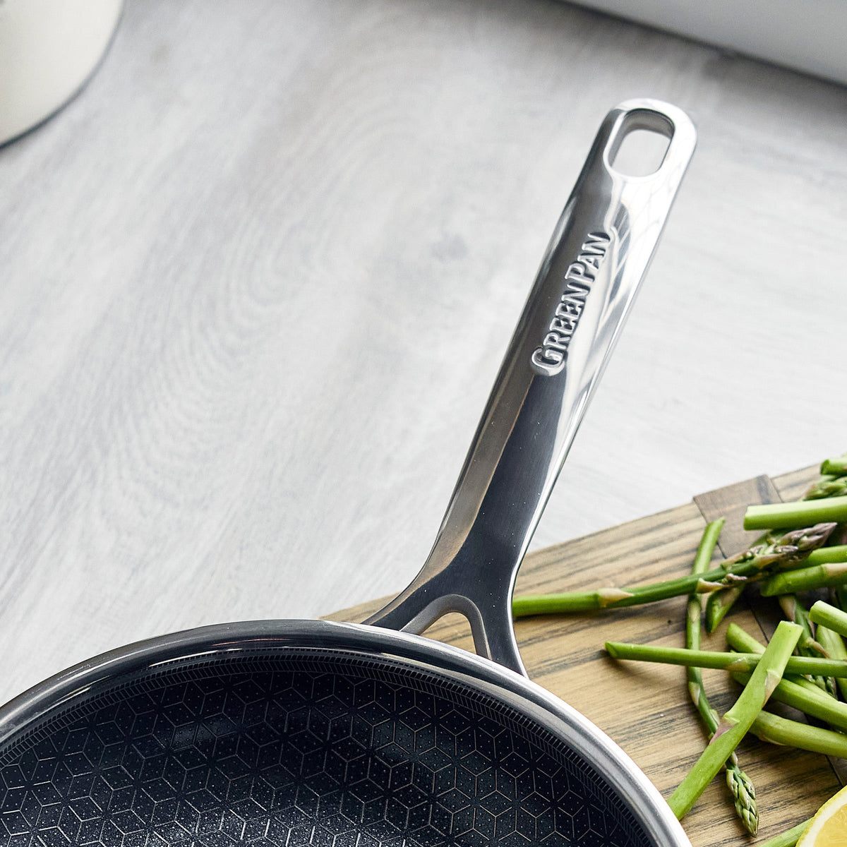 Hybrid ceramic nonstick pan next to chopped green beans on a wooden cutting board.