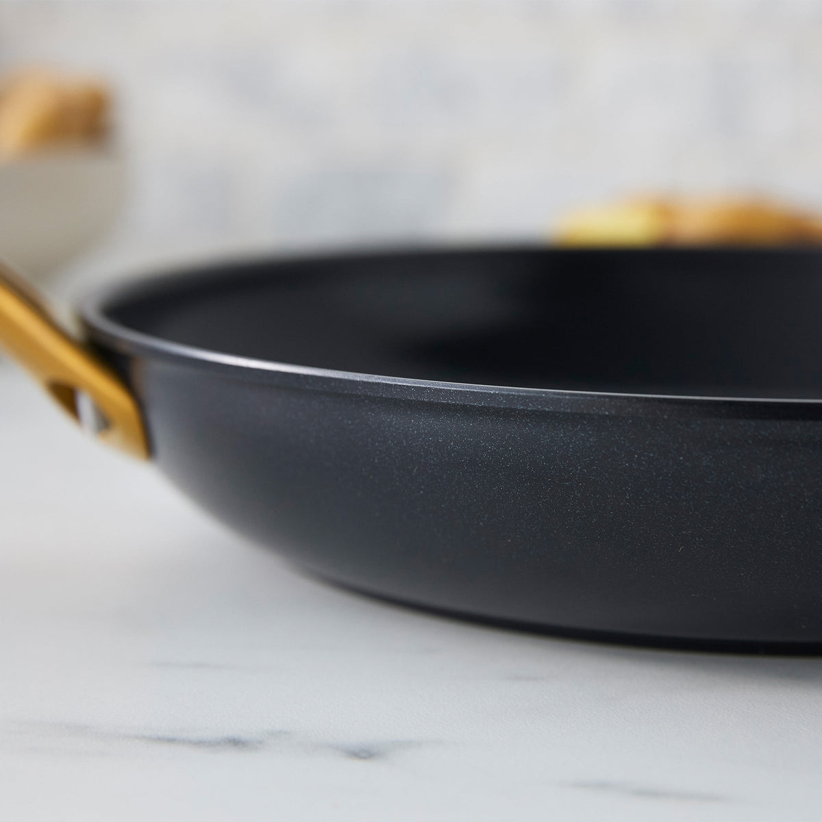 Black frying pan on a marble surface with a blurred background