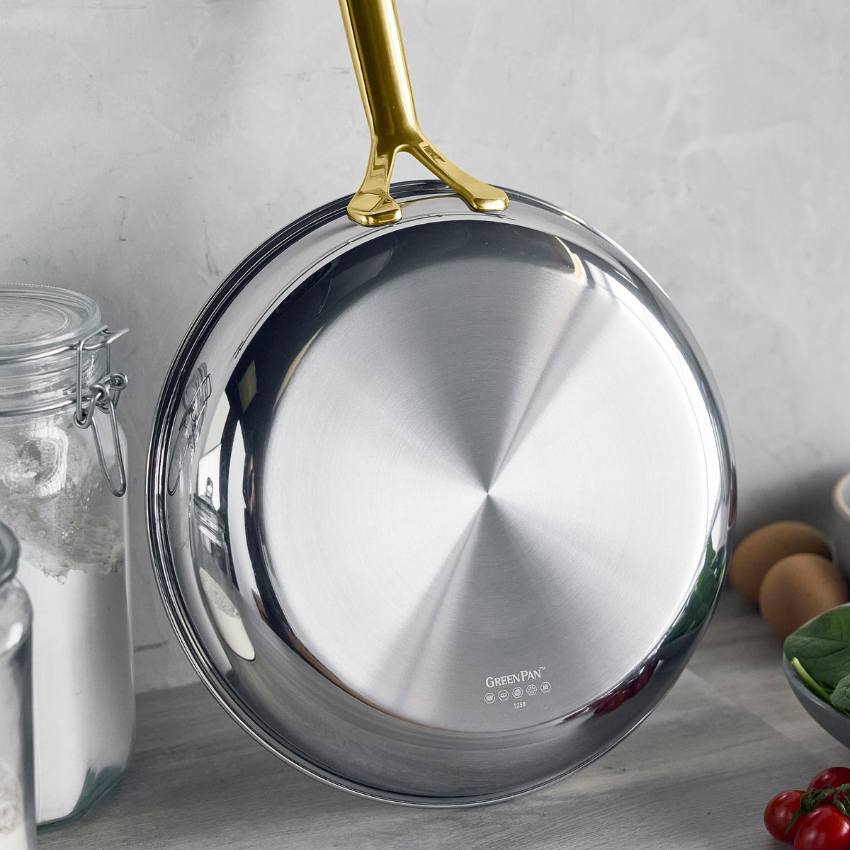 Gold ceramic nonstick frypan set standing upright on a kitchen counter.