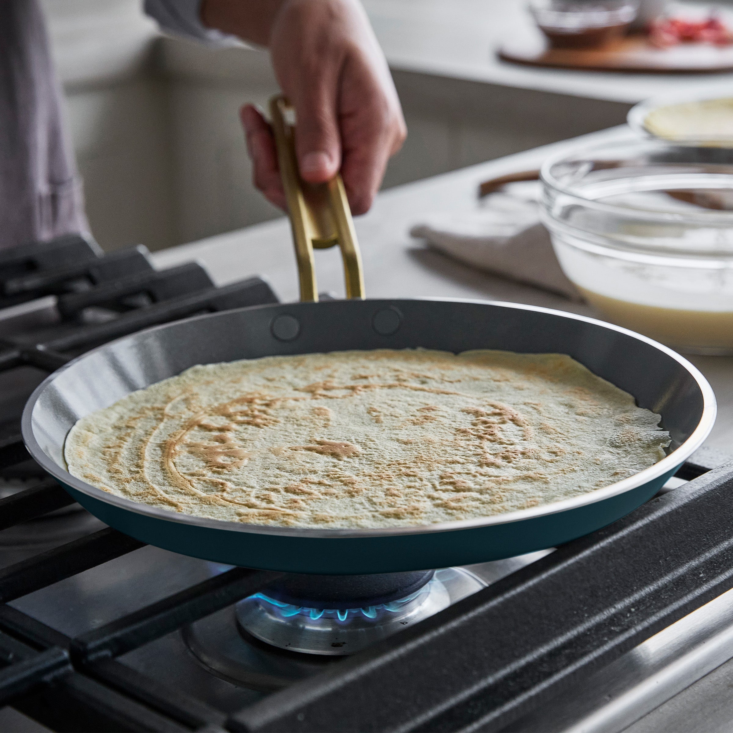 Person cooking a crepe in a pan on a stove