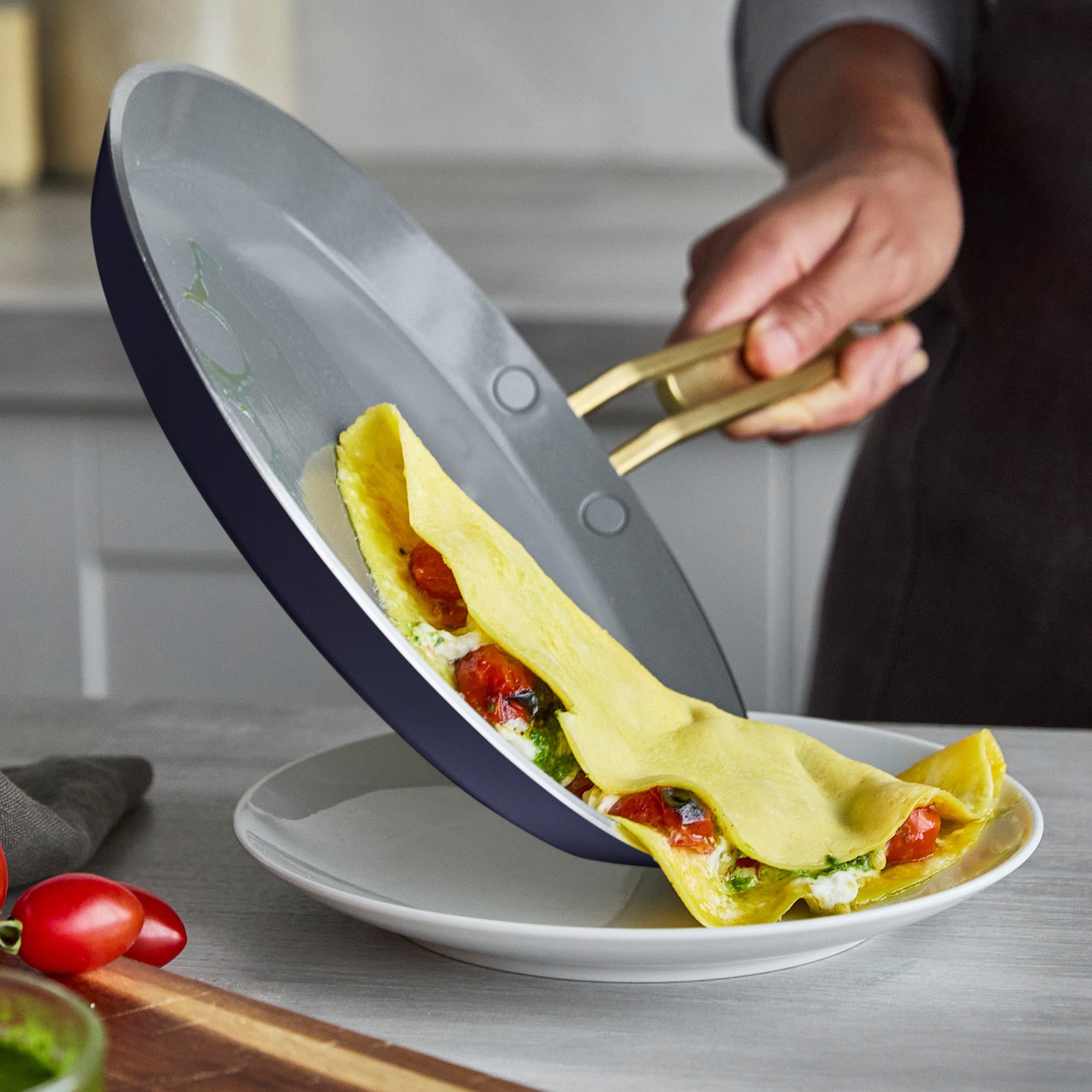 Person sliding a crepe from a pan onto a white plate.