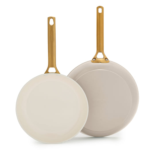 Two taupe ceramic frying pans with gold handles on a white background