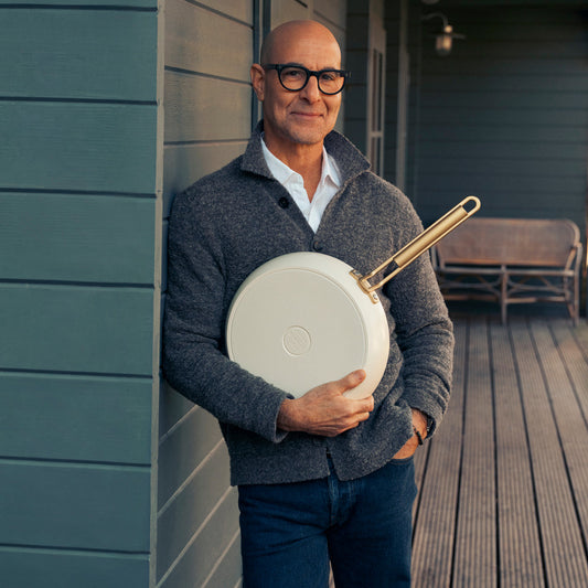 Stanley Tucci holding a white frypan on a porch